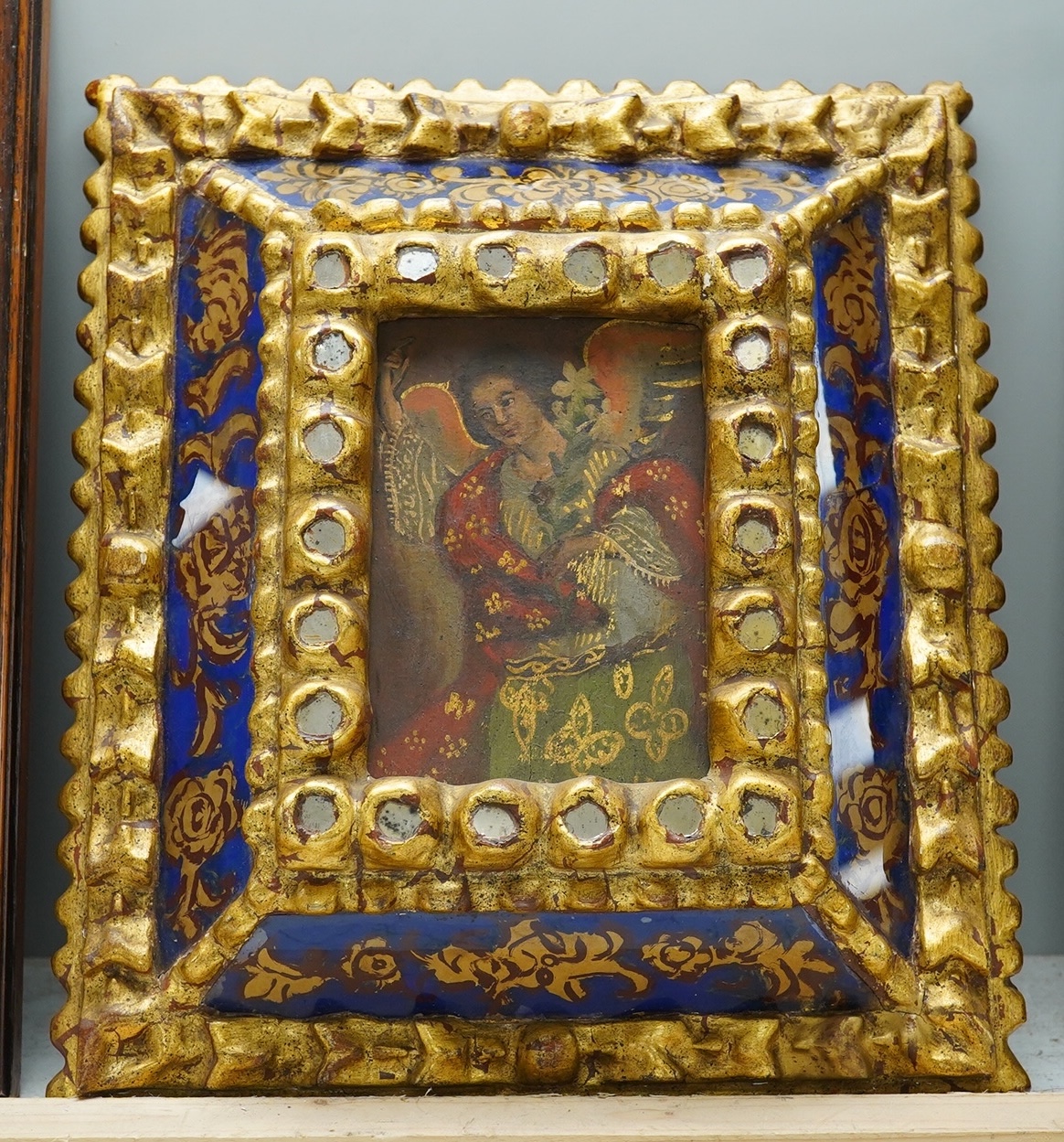 19th century, Retablo oil on board, Study of an angel or saint, 14 x 9cm, housed in an ornate gilt and reverse glass painted frame. Condition - fair